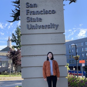 Liu standing on campus in front of SF State sign