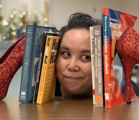 Student with their head on shelf between a row of books