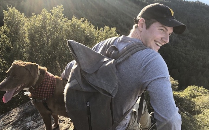 Alex smiling on a hike with his dog