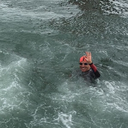 Joeseph Tuman swimming in the San Francisco Bay wearing an orange cap